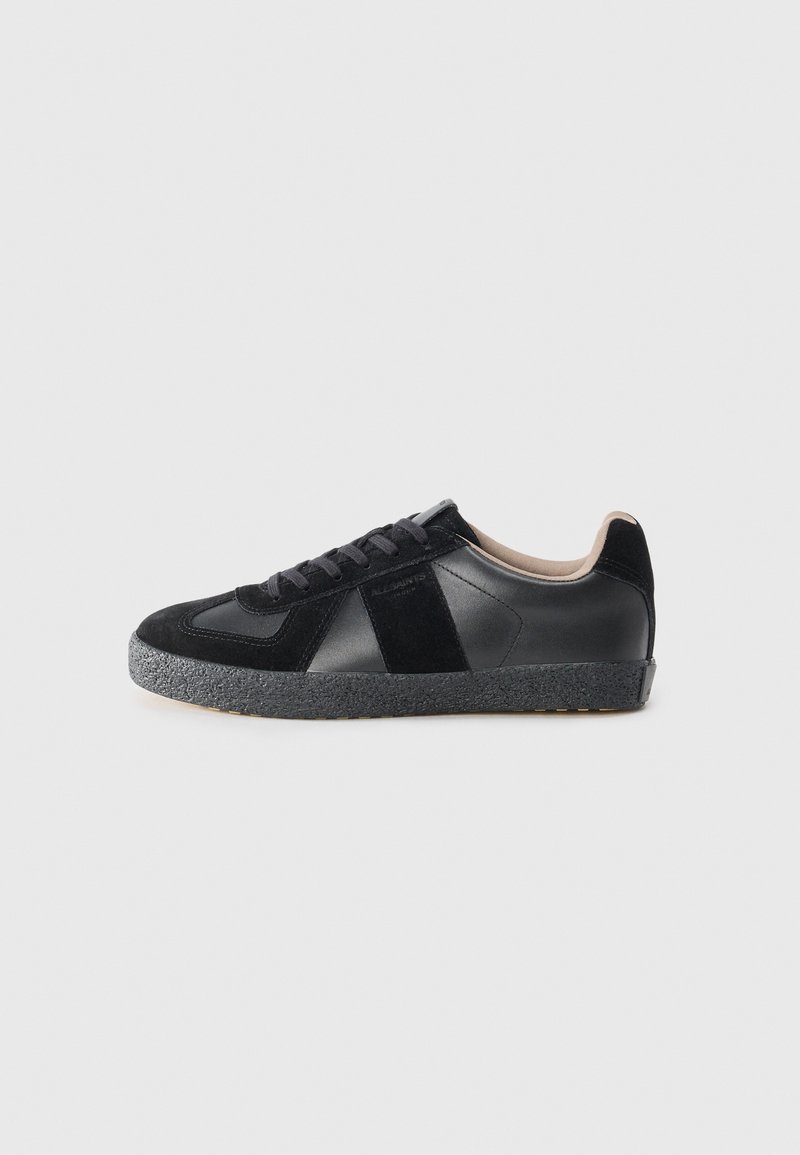 Baskets noires en cuir et en daim, dotées d'une semelle en caoutchouc texturé gris, d'un bout rond et de lacets noirs. Design minimaliste avec des accents.