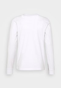 Langärmliges weißes Baumwoll-T-Shirt mit rundem Halsausschnitt und umgeschlagenen Ärmeln. Glatte Textur, einfaches Design, keine sichtbaren Logos oder Muster.