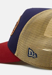 Marineblauer Stoffhut mit einem roten Schirm und einem gelben Netzrücken. Auf der Vorderseite befindet sich ein gesticktes Logo und ein genähtes "N"-Logo an der Seite.