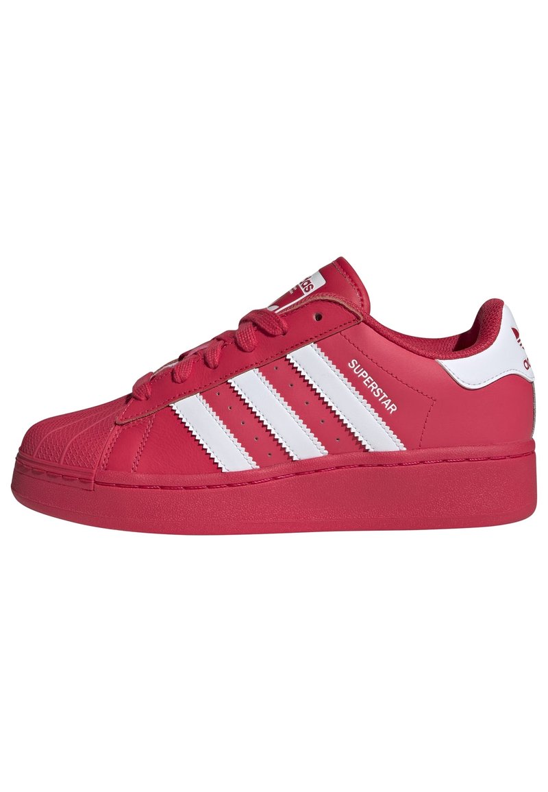 Röd Adidas Superstar-sneaker med vita ränder, snäppa i skalform och "Superstar"-text på sidan, uppvisad mot en vit bakgrund.