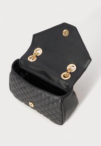 Black quilted handbag with a textured surface, gold hardware accents, double snap closures, and a spacious interior.