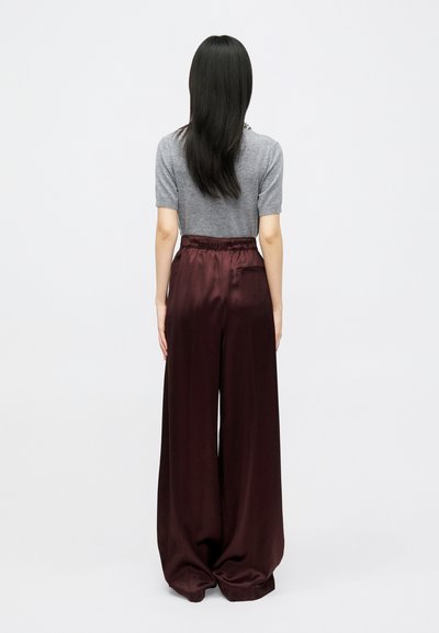 Siv zgornji del s kratkimi rokavi, v kombinaciji s širokimi, visokim pasom, burgundskimi satenskimi hlačami z elastičnim pasom.