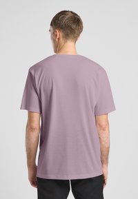 T-shirt corto a maniche corte color lillà con scollatura a girocollo, realizzato in tessuto morbido. Dotato di una vestibilità comoda e di una texture liscia. Vista posteriore mostrata.