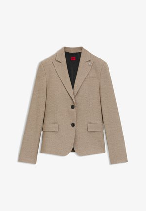 Beige blazer with two black buttons, notched lapels, two front pockets, and a subtle texture; features a branded pin on the left lapel.