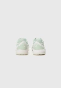 Light green athletic shoes with a textured mesh upper, contrasting white accents, and a rubber outsole, showing rear view.
