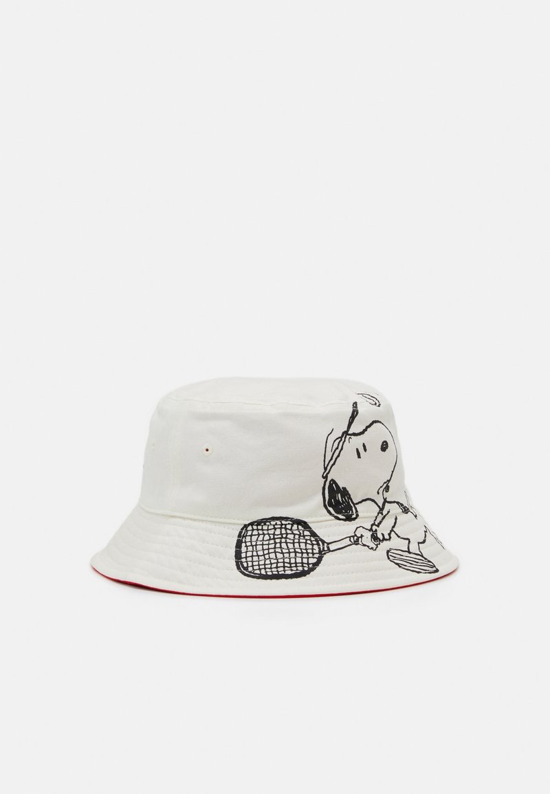 Chapeau seau blanc avec Snoopy tenant une raquette de tennis, prêt à jouer, avec un bord doublé de rouge sur un fond uni.