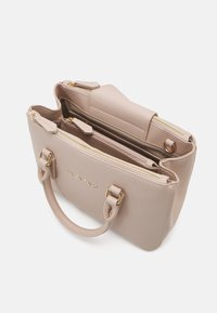 Sac à main en cuir beige avec deux compartiments zippés, des accents en matériel doré et des poignées courtes. Présente un marquage en relief sur le devant.