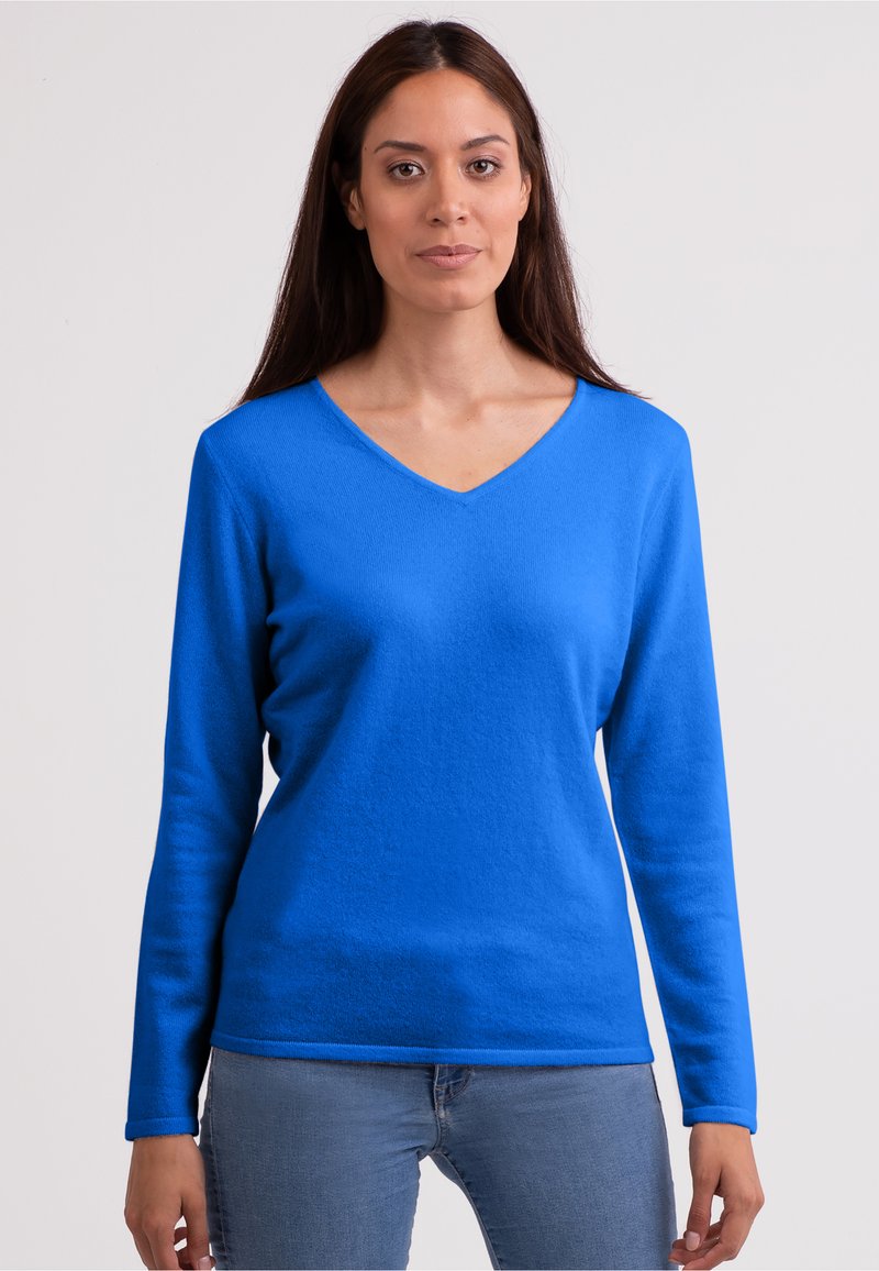 Maglione a maniche lunghe a V in blu brillante, realizzato in tessuto texturizzato. Presenta una forma aderente e polsini a coste. Indossato con jeans blu chiaro.