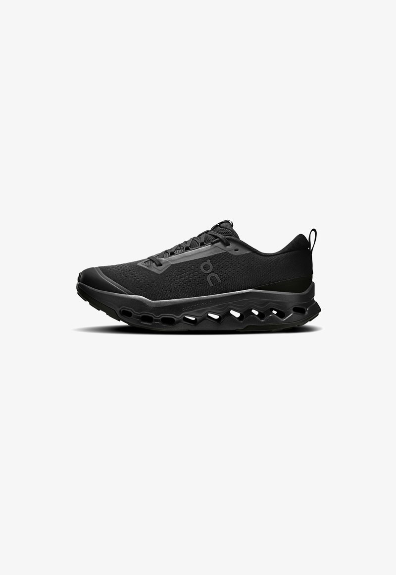 Chaussure de sport noire avec une tige texturée, un bout arrondi et une semelle rembourrée comportant des sections découpées pour la circulation de l'air. Lacets et languette au talon inclus.