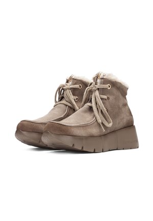 Paire de bottines taupe en daim avec semelles épaisses en caoutchouc, bouts ronds, fermeture à lacets sur le devant et doublure en fourrure blanche visible au niveau du col.