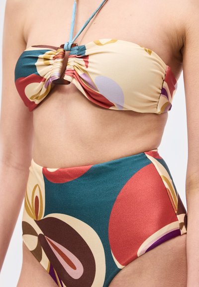 Κοντινό πλάνο ενός ατόμου που φοράει μπικίνι τοπ bandeau με πολύχρωμο, αφηρημένο σχέδιο και μαγιό σλιπ με ψηλή μέση.