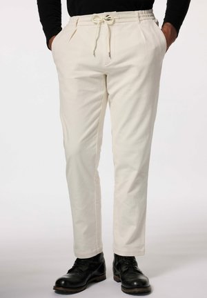Cream-colored trousers with a drawstring waistband, front pleats, and side pockets, made from a textured fabric. Worn with black boots.