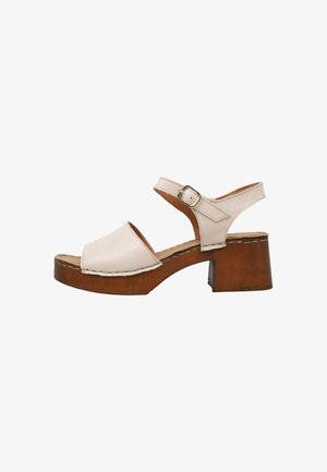 Sandalia beige de cuero con puntera abierta, tacón bloque de madera y tira ajustable en el tobillo con hebilla, vista lateral sobre fondo blanco.