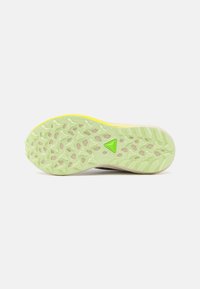 Semelle de chaussure de sport avec surface en caoutchouc vert, présentant un motif de semelle multidirectionnelle et un accent jaune clair le long du bord.