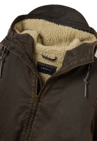 Braune Jacke mit Reißverschluss und einem gemütlichen cremefarbenen Fleecefutter, ausgestattet mit einer Kapuze mit Kordelzug und einem Metallreißverschluss. Glatte Außenseite mit leichter Textur.