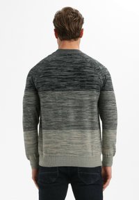 Halli kudumüts, millel on gradientmuster tumedast heledani, tekstureeritud kangas ning soonilised varrukate ja äärte lõpetused.