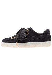 Baskets en daim noir avec des lacets noirs épais et texturés, des œillets dorés, et une semelle en caoutchouc blanche ornée d'un motif discret en éclaboussures.