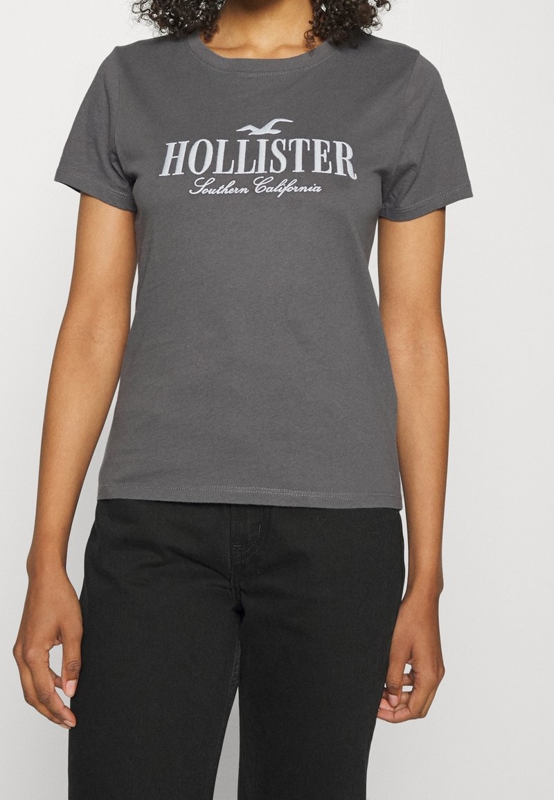 Szara koszulka z krótkim rękawem wykonana z bawełny, z białym logo "HOLLISTER" oraz napisem „Southern California” z przodu. Klasyczny krój z okrągłym dekoltem.