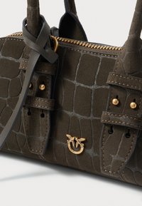 Torebka z ciemnozielonej zamszowej tkaniny w wzór krokodyla, z złotymi akcentami, w tym emblematu z pszczołą oraz regulowanymi paskami. Posiada zamek błyskawiczny.