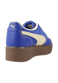 Baskets en cuir et suède bleu avec des accents crème, des détails cousus, un logo sur le talon et une semelle plateforme marron texturée.