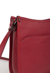 Borsa a spalla in pelle rossa con superficie testurizzata, cuciture in cima e un design piatto e minimalista con una tracolla regolabile abbinata.