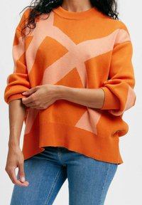 Orange och rosa mönstrad tröja med ribbad rund halsringning och överdimensionerade ärmar; något cropped fåll; stickad tyg.