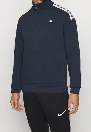 Marineblaue Half-Zip-Sweatshirt mit halblangen Ärmeln, Kängurutasche und weißen sowie orange gemusterten Seitenstreifen. Kappa-Logo auf der Brust.