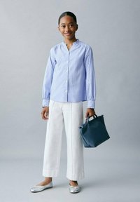 Cămașă cu dungi albastre și albe, pantaloni largi albi, balerini argintii și o geantă de umăr albastră închis cu mânere scurte.