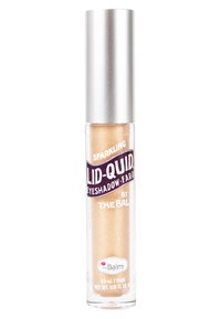 Vloeibare gouden oogschaduw in een doorzichtig tubetje met een zilveren dop. Heeft een glinsterende textuur en is gelabeld als "Sparkling Lid-Quid" van theBalm.