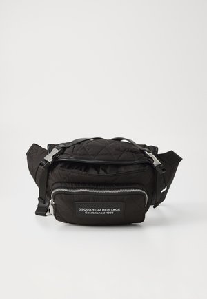 Zwarte gequiltte stoffen tas met ritssluiting, verstelbare schouderband en een voorvak met een merkembleem. Accenten van zilveren hardware.