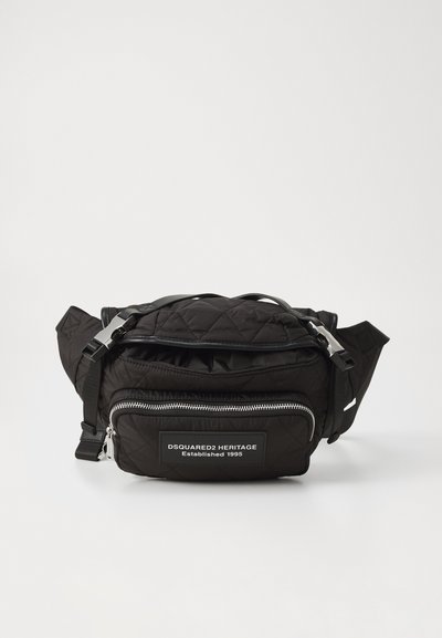 Black quilted fabric bag with a zipper closure, adjustable strap, and a front pocket featuring a branded patch. Silver hardware accents.