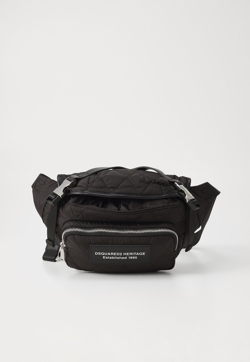 Black quilted fabric bag with a zipper closure, adjustable strap, and a front pocket featuring a branded patch. Silver hardware accents.