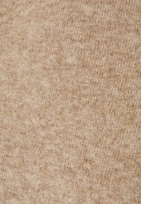 Beige textured fabric with a soft, fuzzy surface, featuring a subtle pattern that adds depth to the overall appearance.