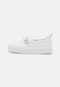 Vit slip-on-sneaker med övre del i mjuk, syntetisk läder, tjock räfflad sula och en dekorativ kristalldetalj på sidan.