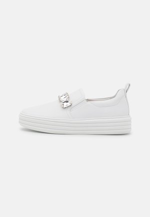 White slip-on sneaker with a smooth faux leather upper, thick ridged sole, and a decorative crystal accent on the side.