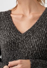 Charcoal gray knitted sweater with a deep V-neck, vertical ribbed texture, and subtle white flecks. Made from soft, warm material.