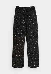 Svarta vida byxor med vita prickar, med en knytning i midjan och en slät tygtextur. Benen är avkortade vid anklarna.