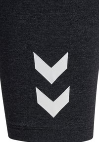 Svarta texturerade tygshorts med ett vitt nedåtriktat chevronmönster på vänster sida, med en åtsittande design och sydd fåll.