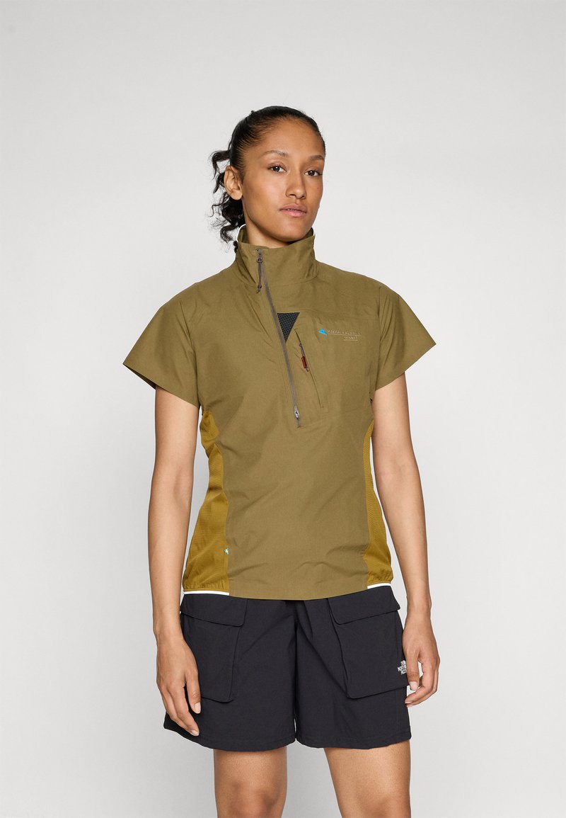 Olive green short-sleeve top with a high collar, front zipper, and mesh panels, paired with dark shorts featuring large cargo pockets.