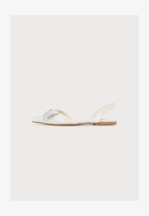 Λευκό επίπεδο παπούτσι slingback με μυτερή μύτη και διακοσμητικό ασημένιο φιόγκο από στρας πάνω σε απλό φόντο.