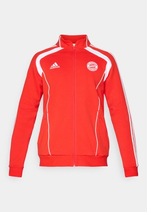 Rød hettejakke med hvite detaljer, med lange ermer, høy krage og FC Bayern München-logo på brystet. Mykt tekstilmateriale.