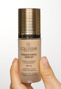 Fond de teint Collistar Fondotinta Unico dans un flacon transparent avec un capuchon en or texturé, comportant un SPF 15 et des inscriptions en noir détaillant les informations sur le produit.