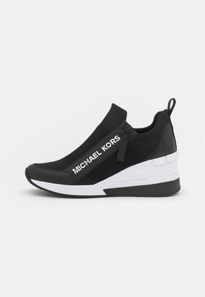 Sneaker nera con tomaia in rete e materiale sintetico, caratterizzata da una suola a zeppa, dettagli bianchi, chiusura con cerniera e marchio "MICHAEL KORS".