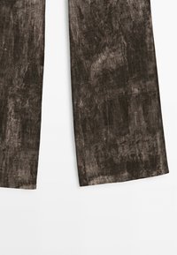 Pantalon marron à jambes larges avec une finition en tissu texturé légèrement usé, présenté sur fond blanc.