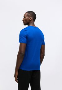 T-shirt blu a maniche corte dal design aderente, realizzato in morbido cotone. Presenta un collo rotondo e una texture liscia, abbinato a pantaloni neri.