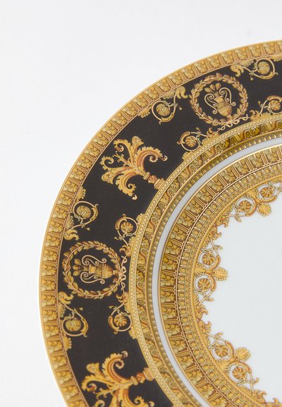 Dekoratívny obedový tanier s čiernym pozadím, zdobený zložitými zlatými vzormi, bohatými okrajmi a centrálnou bielou oblasťou.