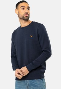 Marineblauwe sweatshirt van een katoenmix, met een ronde halslijn en lange mouwen, voorzien van een klein oranje embleem op de linkerborst.