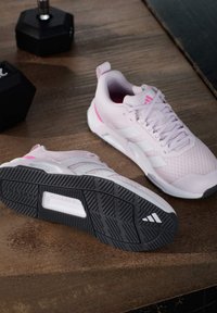 Hellrosa Sportschuhe mit einer strukturierten Oberseite, weißen Streifen und einer schwarzen Gummiaußensohle mit einem Profilmuster.