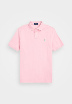 Hellrosa kurzärmeliges Poloshirt mit Kragen und Zwei-Knopf-Leiste, versehen mit einem kleinen grünen bestickten Logo auf der Brust.