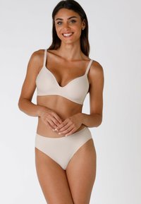 Reggiseno beige senza cuciture e slip abbinati, in morbido tessuto, con un leggero contouring, spalline regolabili, finitura liscia e hardware minimale.